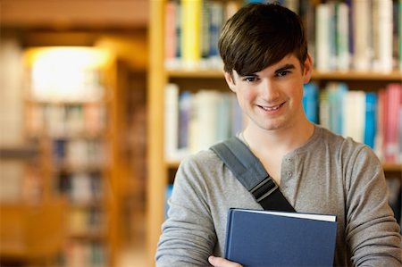 simsearch:400-05669803,k - Smiling young student holding a book in a library Stock Photo - Budget Royalty-Free & Subscription, Code: 400-05670290