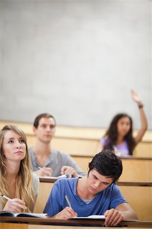 Portrait of students taking notes while their classmate is raising her hand in an amphitheater Stock Photo - Budget Royalty-Free & Subscription, Code: 400-05684339