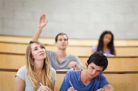 Student raising his hand while his classmates are taking notes in an amphithater Stock Photo - Budget Royalty-Free & Subscription, Code: 400-05684341