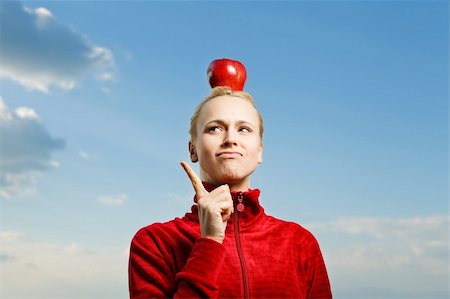 Young attractive woman outdoor holding red apple on her head and thinking about something with a blue sky on a background Stock Photo - Budget Royalty-Free & Subscription, Code: 400-05706453