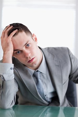 simsearch:400-05709555,k - Close up of young businessman sitting behind a table after getting bad news Stock Photo - Budget Royalty-Free & Subscription, Code: 400-05709569