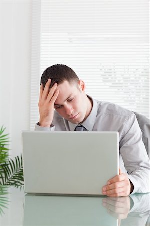 simsearch:400-05709564,k - Close up of disappointed young businessman looking at his laptop Stock Photo - Budget Royalty-Free & Subscription, Code: 400-05709631