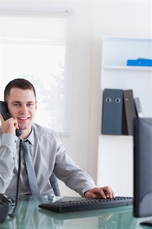 simsearch:400-05710264,k - Smiling businessman listening to caller while typing Stock Photo - Budget Royalty-Free & Subscription, Code: 400-05709695