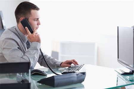 simsearch:400-05710264,k - Young businessman typing while on the phone Stock Photo - Budget Royalty-Free & Subscription, Code: 400-05709690