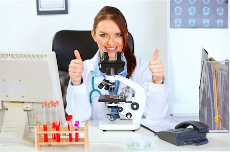 Smiling female medical doctor using microscope in laboratory and showing thumbs up gesture Stock Photo - Budget Royalty-Free & Subscription, Code: 400-05701722