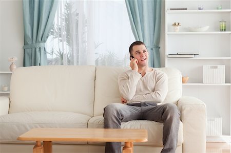 simsearch:400-04212823,k - Man on the phone while sitting on his sofa against a white background Stock Photo - Budget Royalty-Free & Subscription, Code: 400-05715318
