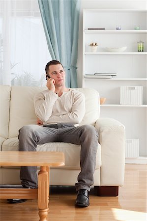 simsearch:400-04212823,k - Portrait of a man on the phone while sitting on his sofa in his living room Stock Photo - Budget Royalty-Free & Subscription, Code: 400-05715319