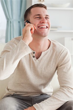 simsearch:400-04212823,k - Portrait of a laughing man making a phone call while sitting on a sofa against a white background Stock Photo - Budget Royalty-Free & Subscription, Code: 400-05715327