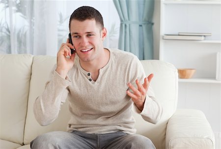 simsearch:400-04212823,k - Man talking through the phone while sitting on a couch in his living room Stock Photo - Budget Royalty-Free & Subscription, Code: 400-05715330