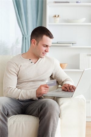 simsearch:400-04410667,k - Portrait of a young man shopping online in his living room Stock Photo - Budget Royalty-Free & Subscription, Code: 400-05715534