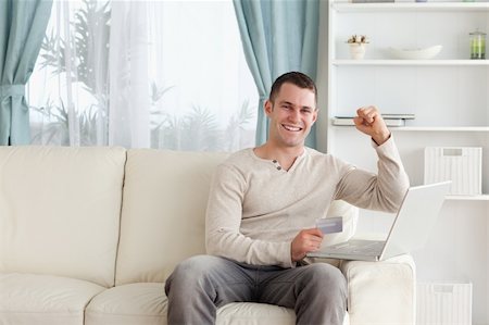 face to internet technology - Happy man shopping online with the fist up in his living room Photographie de stock - Aubaine LD & Abonnement, Code: 400-05715536