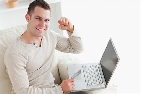 face to internet technology - Young man shopping online with the fist up in his living room Stock Photo - Budget Royalty-Free & Subscription, Code: 400-05715539