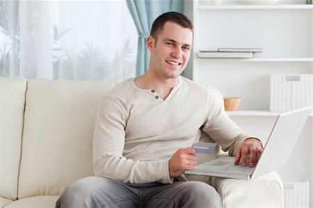 simsearch:400-04410667,k - Smiling man shopping online in his living room Stock Photo - Budget Royalty-Free & Subscription, Code: 400-05715532