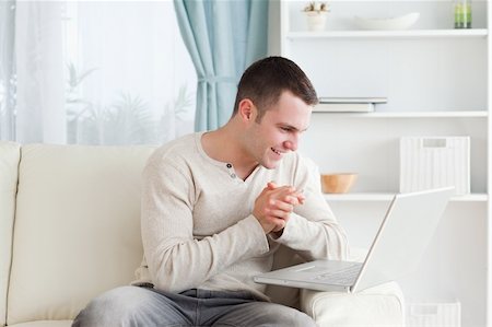 simsearch:400-04412244,k - Happy man using a laptop in his living room Stock Photo - Budget Royalty-Free & Subscription, Code: 400-05715552