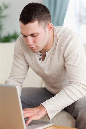 simsearch:400-04412244,k - Portrait of a young man using a notebook in his living room Stock Photo - Budget Royalty-Free & Subscription, Code: 400-05715566