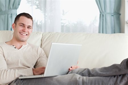 simsearch:400-04412244,k - Smiling man relaxing with a notebook in his living room Stock Photo - Budget Royalty-Free & Subscription, Code: 400-05715589