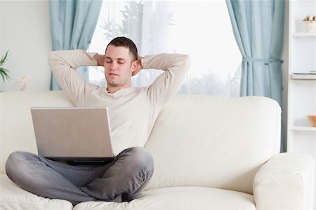simsearch:400-04412244,k - Good looking man using a notebook in his living room Stock Photo - Budget Royalty-Free & Subscription, Code: 400-05715599