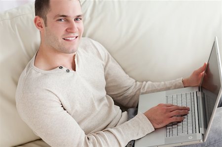 simsearch:400-04412244,k - Young man relaxing with a notebook in his living room Stock Photo - Budget Royalty-Free & Subscription, Code: 400-05715591
