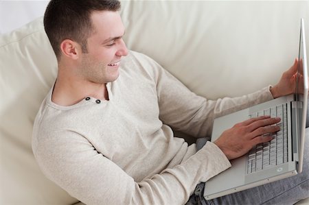 simsearch:400-04412244,k - Happy man relaxing with a notebook in his living room Stock Photo - Budget Royalty-Free & Subscription, Code: 400-05715592