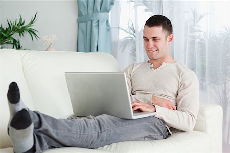 simsearch:400-04412244,k - Smiling man working with his laptop in his living room Stock Photo - Budget Royalty-Free & Subscription, Code: 400-05715614