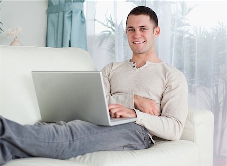 simsearch:400-04412244,k - Smiling man working with his notebook in his living room Stock Photo - Budget Royalty-Free & Subscription, Code: 400-05715615