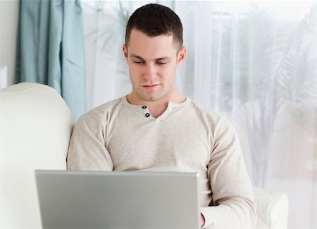 simsearch:400-04412244,k - Young man working with his notebook in his living room Stock Photo - Budget Royalty-Free & Subscription, Code: 400-05715616