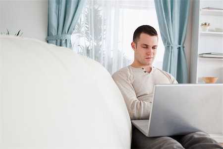 simsearch:400-04412244,k - Handsome man working with his notebook in his living room Stock Photo - Budget Royalty-Free & Subscription, Code: 400-05715618