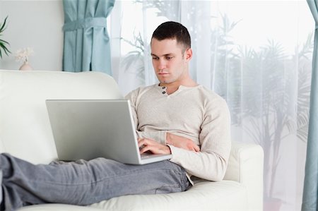 simsearch:400-04412244,k - Young man working with his laptop in his living room Stock Photo - Budget Royalty-Free & Subscription, Code: 400-05715613