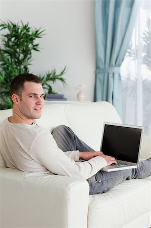 simsearch:400-04412244,k - Portrait of a man lying on his couch with a notebook while looking at the camera Stock Photo - Budget Royalty-Free & Subscription, Code: 400-05715645