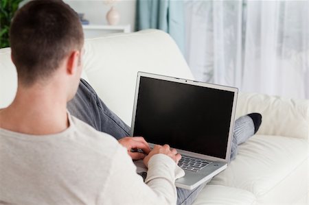 simsearch:400-04412244,k - Man lying on his couch to use a laptop in his living room Stock Photo - Budget Royalty-Free & Subscription, Code: 400-05715640