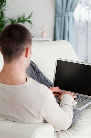 simsearch:400-04412244,k - Portrait of a man lying on his couch to use a laptop in his living room Stock Photo - Budget Royalty-Free & Subscription, Code: 400-05715641
