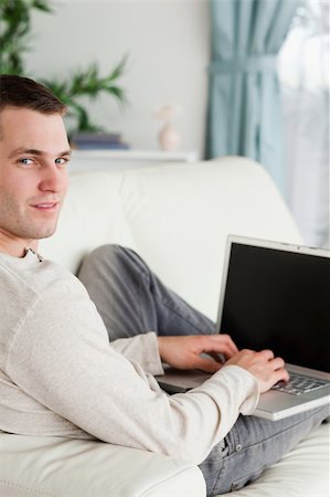 simsearch:400-04412244,k - Portrait of a man lying on his couch with a laptop looking at the camera Stock Photo - Budget Royalty-Free & Subscription, Code: 400-05715642