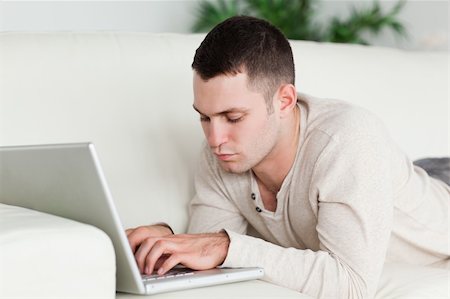 simsearch:400-04412244,k - Man lying on a sofa using a laptop in his living room Stock Photo - Budget Royalty-Free & Subscription, Code: 400-05715654