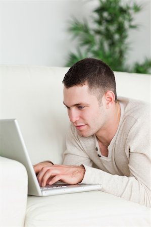 simsearch:400-04412244,k - Portrait of a man lying on a sofa using a laptop in his living room Stock Photo - Budget Royalty-Free & Subscription, Code: 400-05715657