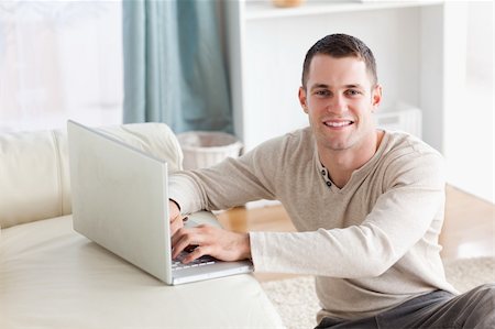 simsearch:400-04412244,k - Smiling man sitting on a carpet posing with a notebook in his living room Stock Photo - Budget Royalty-Free & Subscription, Code: 400-05715678