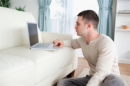 simsearch:400-04412244,k - Man sitting on a carpet while using a laptop in his living room Stock Photo - Budget Royalty-Free & Subscription, Code: 400-05715672