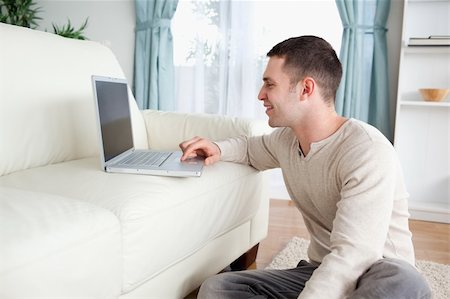 simsearch:400-04412244,k - Smiling man sitting on a carpet while using a laptop in his living room Stock Photo - Budget Royalty-Free & Subscription, Code: 400-05715673