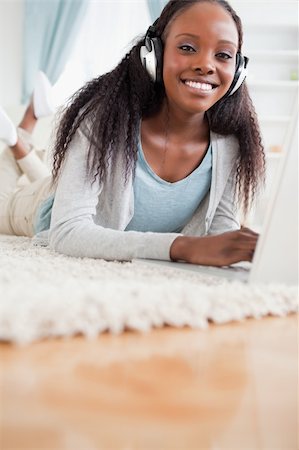 simsearch:400-05717206,k - Close up of young woman lying on floor with her laptop listening to music Stock Photo - Budget Royalty-Free & Subscription, Code: 400-05717194