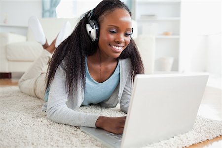 simsearch:400-05716451,k - Smiling woman lying on floor with her notebook listening to music Stock Photo - Budget Royalty-Free & Subscription, Code: 400-05717196