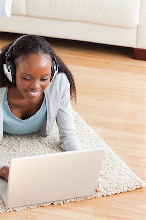 simsearch:400-05716451,k - Close up of smiling woman lying on floor with laptop listening to music Stock Photo - Budget Royalty-Free & Subscription, Code: 400-05717209