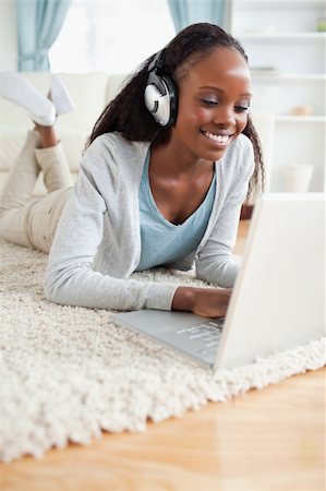 simsearch:400-05717206,k - Close up of smiling woman lying on floor with her laptop enjoying music Stock Photo - Budget Royalty-Free & Subscription, Code: 400-05717201