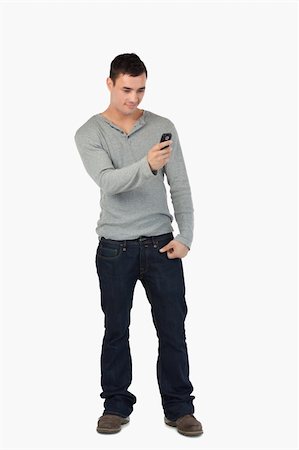 simsearch:400-06632132,k - Young male standing and reading text message against a white background Stock Photo - Budget Royalty-Free & Subscription, Code: 400-05718556