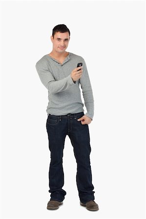 simsearch:400-06632132,k - Young male writing text message while standing against a white background Stock Photo - Budget Royalty-Free & Subscription, Code: 400-05718557