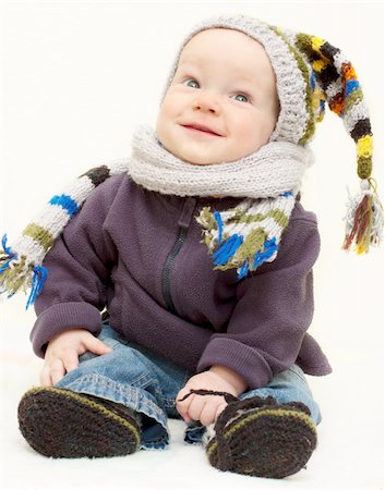 Cute baby boy in knitted handmade hat, scarf and bootees is sitting  with happy smiling face Stock Photo - Budget Royalty-Free & Subscription, Code: 400-05719006