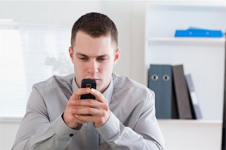 simsearch:400-05710264,k - Businessman typing a textmessage on his cellphone Stock Photo - Budget Royalty-Free & Subscription, Code: 400-05710254