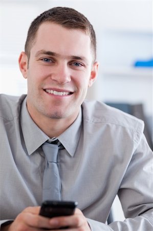 simsearch:400-05710264,k - Close up of smiling young businessman with cellphone in his hands Stock Photo - Budget Royalty-Free & Subscription, Code: 400-05710278