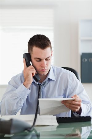 simsearch:400-05710264,k - Close up of young businessman looking at a letter while on the phone Stock Photo - Budget Royalty-Free & Subscription, Code: 400-05710306