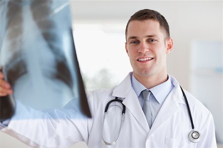 simsearch:400-05710403,k - Smiling young doctor looking at x-ray in his hands Stock Photo - Budget Royalty-Free & Subscription, Code: 400-05710425