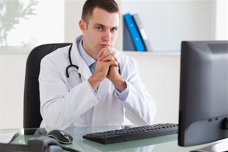 simsearch:400-05710403,k - Young doctor sitting behind his desk Stock Photo - Budget Royalty-Free & Subscription, Code: 400-05710457