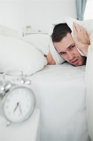 simsearch:6109-06194878,k - Portrait of a man covering his ears with a duvet while his alarm clock is ringing in his bedroom Stock Photo - Budget Royalty-Free & Subscription, Code: 400-05737286
